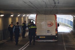 Bestelbus gevuld met pakketjes rijdt zich klem onder viaduct