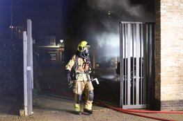 Auto in brand achter woningen in Den Helder