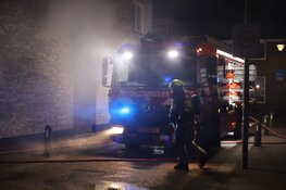 Auto in brand achter woningen in Den Helder